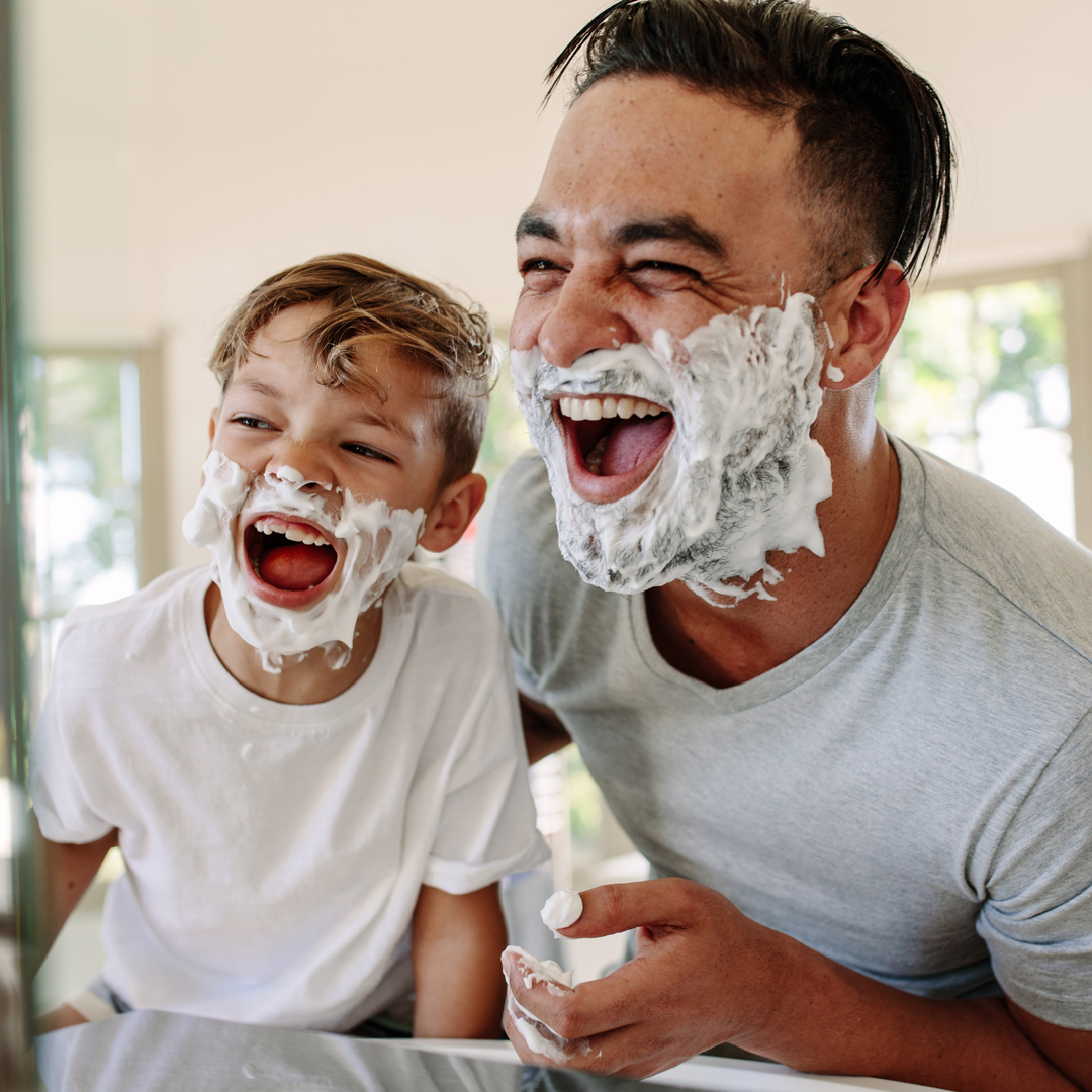 A man and a boy with shaving cream on their faces