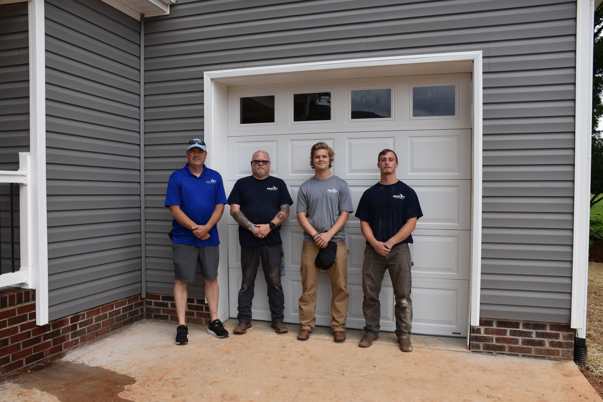 A group of men are standing in front of a garage door.