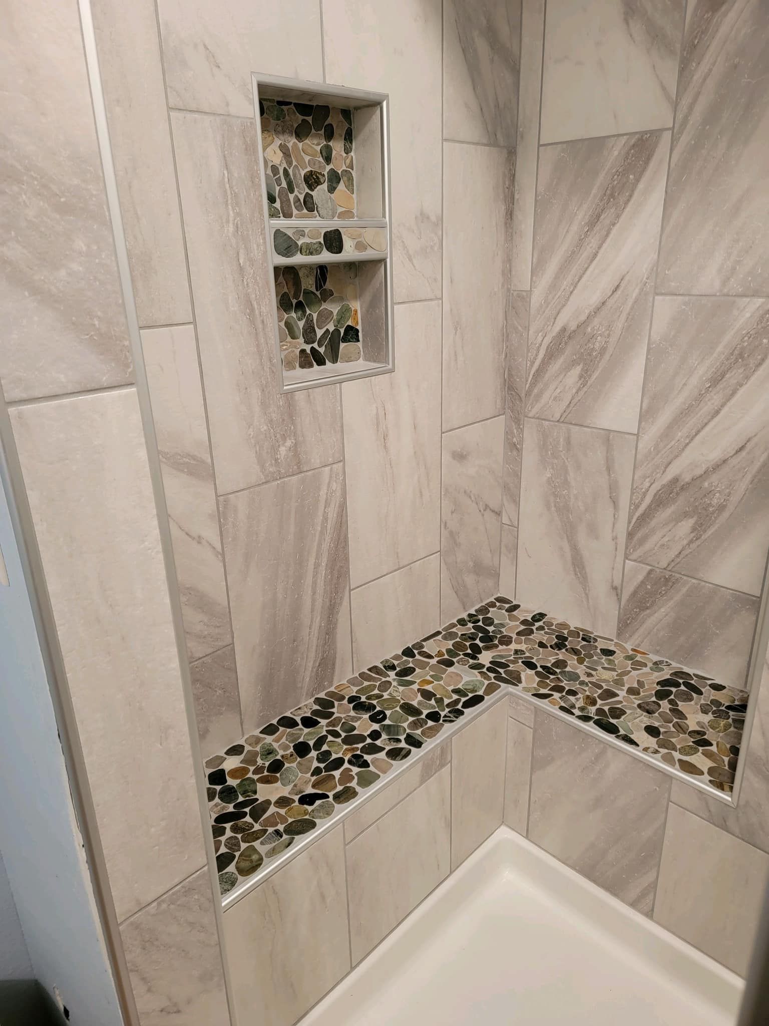 A shower with a bench and a shelf in it.