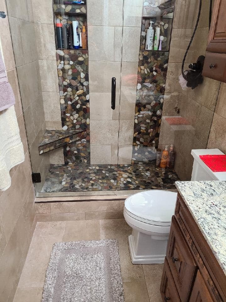 A bathroom with a toilet , sink and walk in shower.