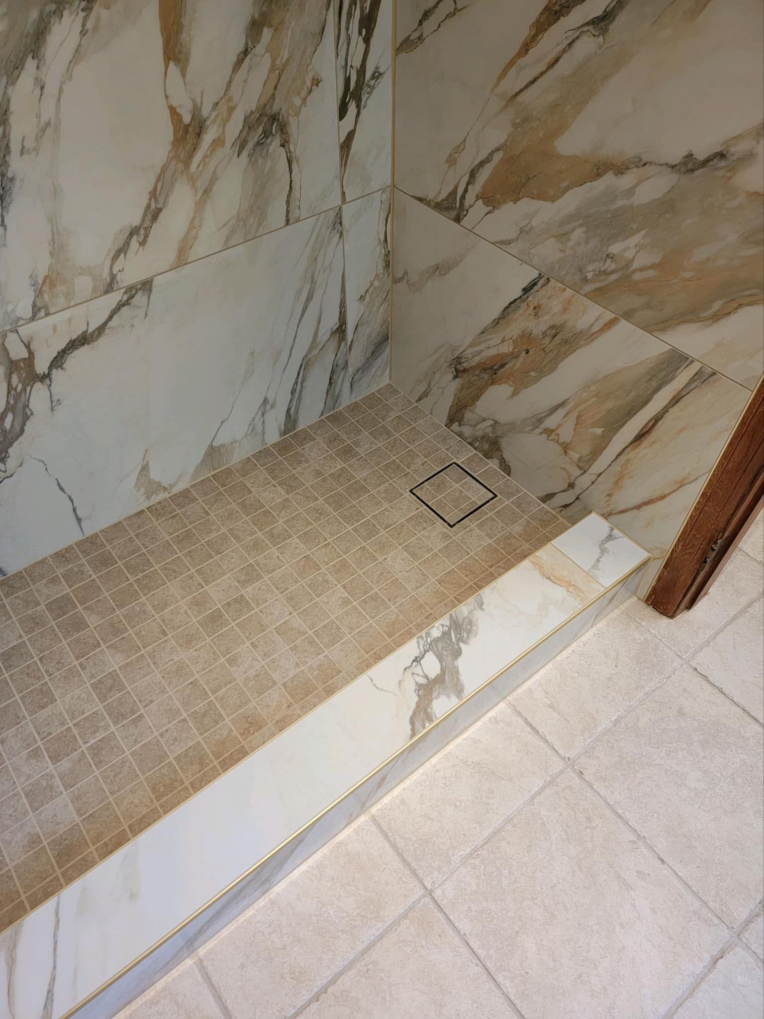 A bathroom with marble tiles and a walk in shower