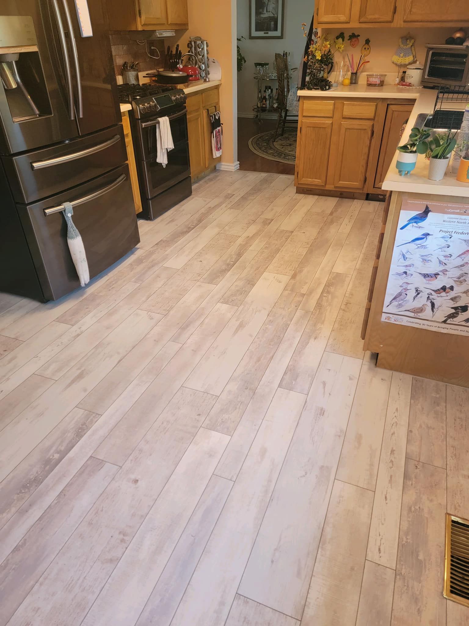 A kitchen with a wooden floor , stove , refrigerator , and sink.