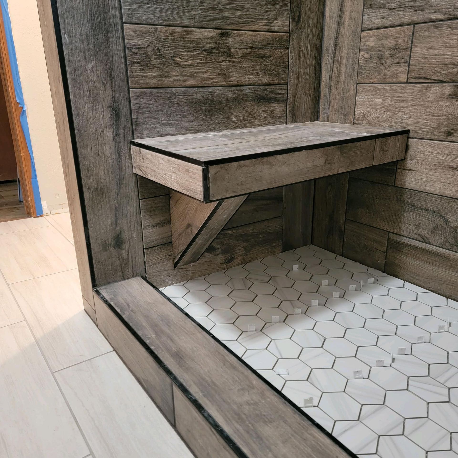 A shower with a wooden shelf and a tiled floor
