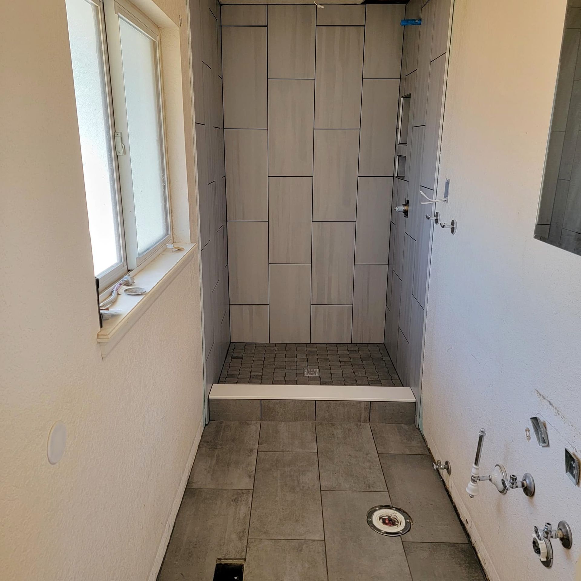 a bathroom with a walk in shower and a window .
