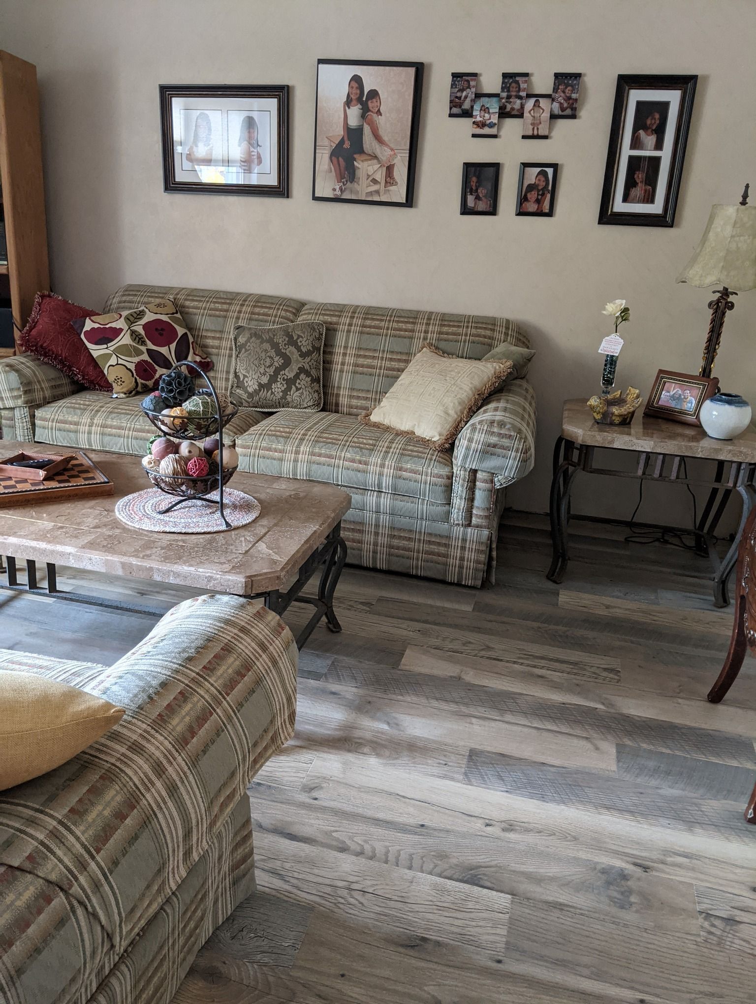 a living room with a couch , chair , coffee table and pictures on the wall .
