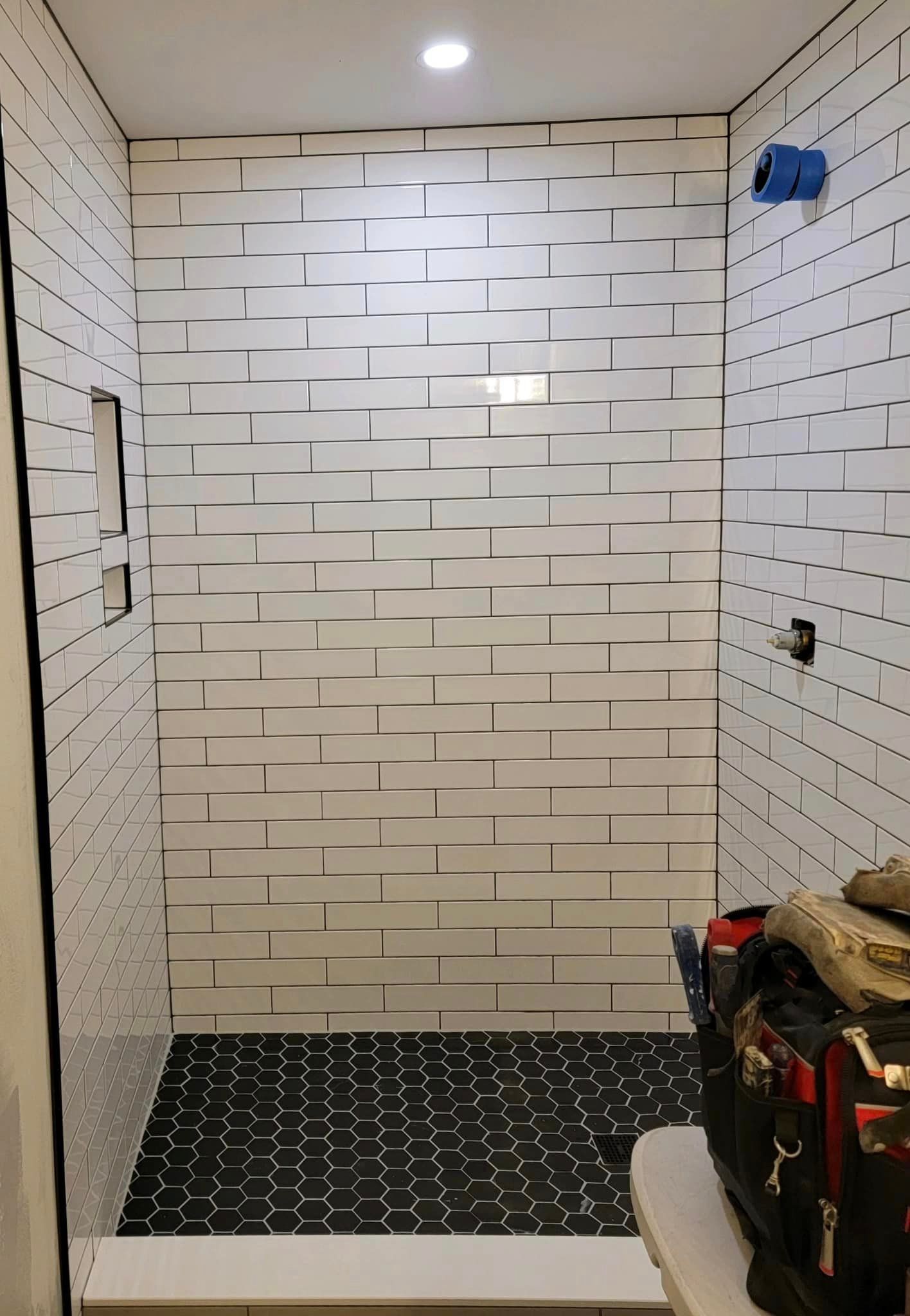 a bathroom with white tiles on the walls and black tiles on the floor .