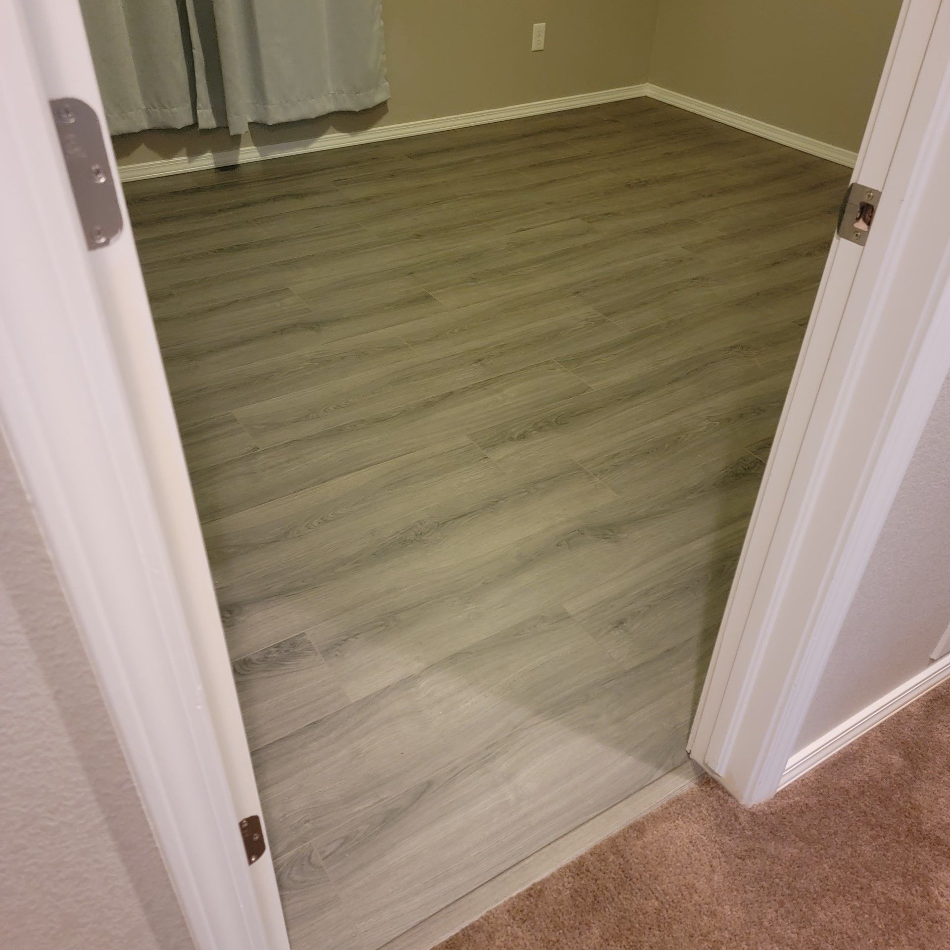 A room with a wooden floor and a doorway leading to it.