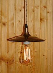 Bronze pendant light fixture with Edison bulb against a wood panel background.
