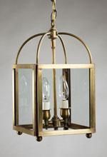 Brass lantern with two light bulbs, clear glass panes, and arched top.