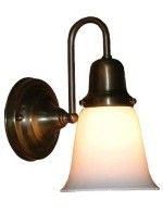 Wall-mounted brass light fixture with a bell-shaped, frosted white glass shade.