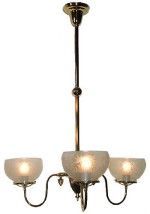 Three-light brass chandelier with frosted glass bowls, ceiling mounted, lit.