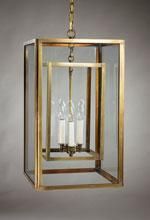 Brass and glass lantern with inner and outer rectangular frames, hanging from a chain; three candle-style lights.