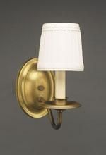 Brass wall sconce with a white lampshade on a gray wall.