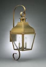 Brass outdoor wall-mounted lantern with textured glass panels, two candle-shaped bulbs, and a curved arm.