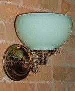 Aqua-colored glass wall sconce with chrome fixture mounted on a brick wall.