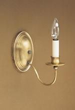 Brass wall sconce with a candle-shaped light bulb on a brown wall.