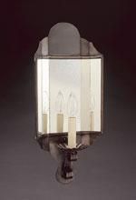 Dark metal outdoor wall lantern with glass panes and three candle-style lights.
