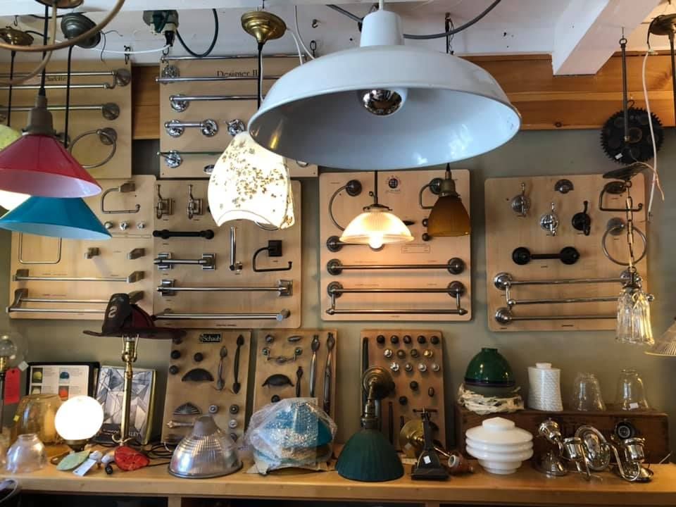 A shop displays various vintage light fixtures and hardware mounted on wooden boards.