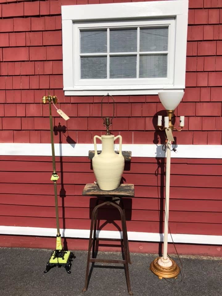 Three lamps and a stool against a red wall with a white window.