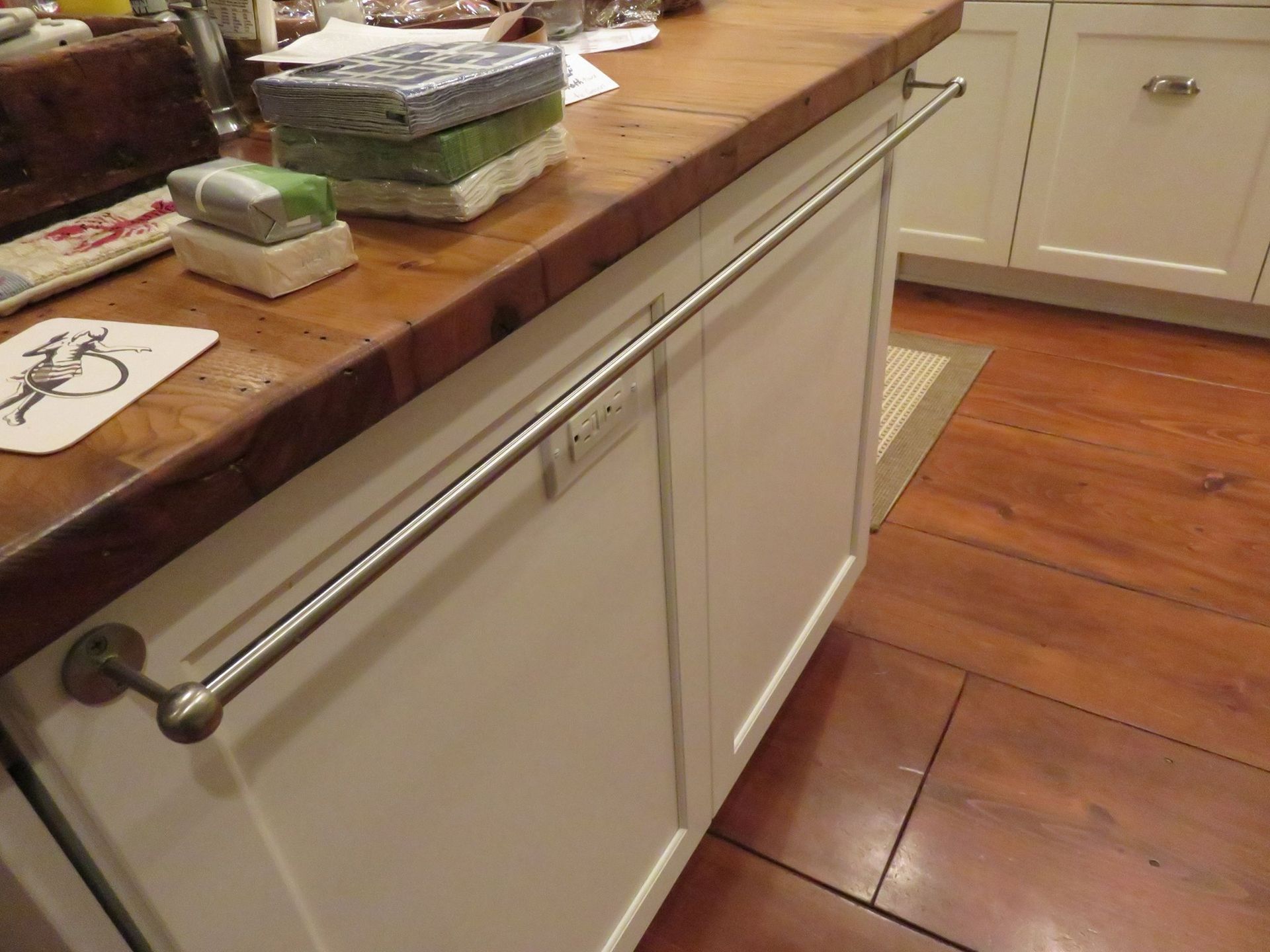A kitchen island with a wood countertop and a towel bar attached to the white cabinet.