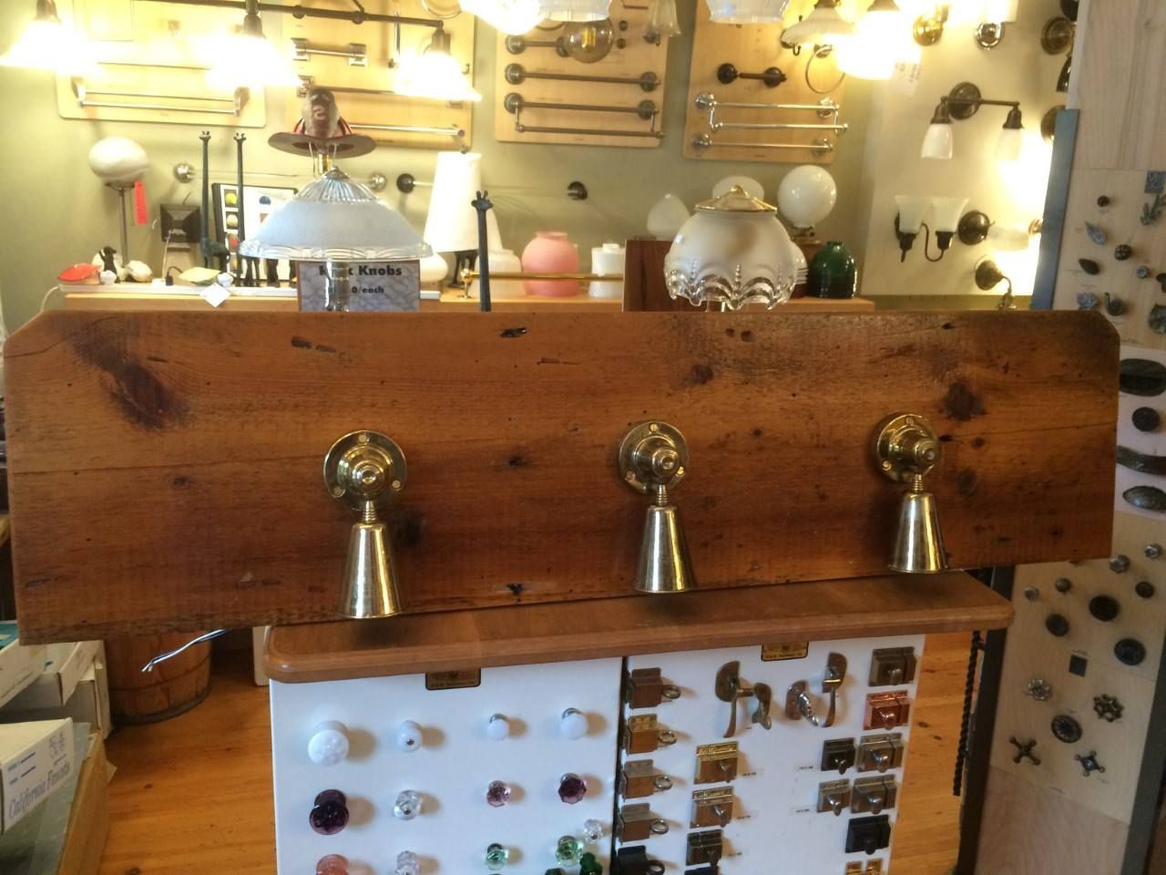 Wooden board with three brass hooks displayed in a store setting.