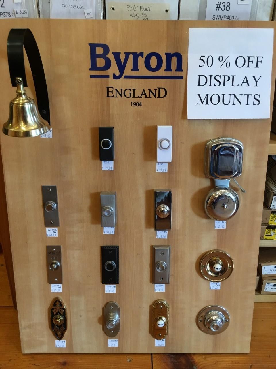 Display of Byron England doorbells and bells on a wooden board; sign says 