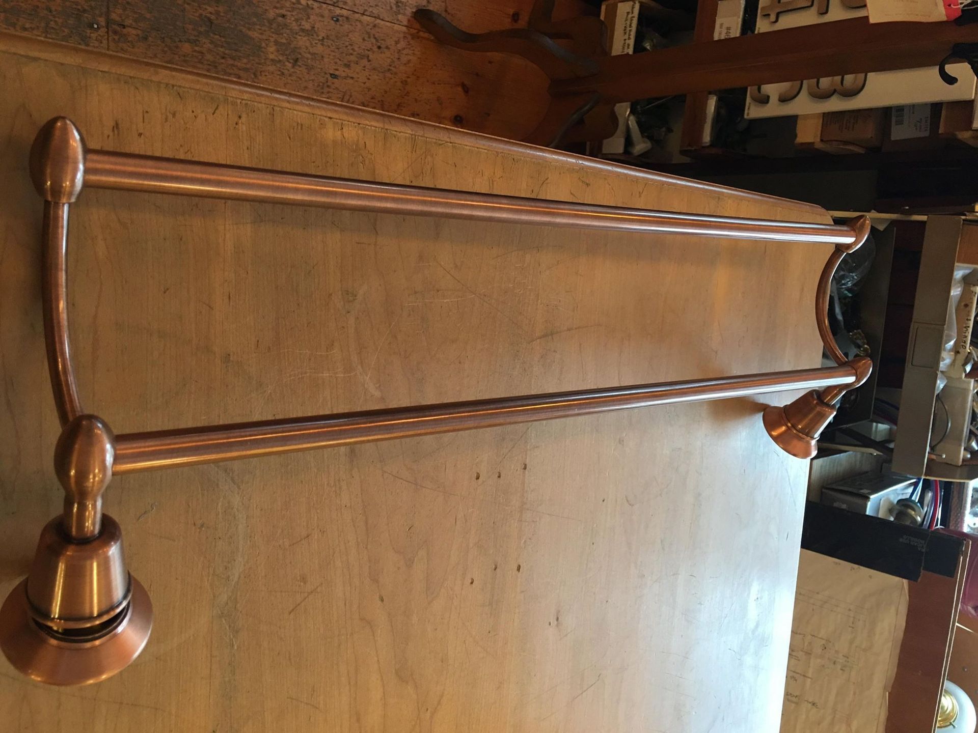 Copper double towel bar mounted on a wooden wall.