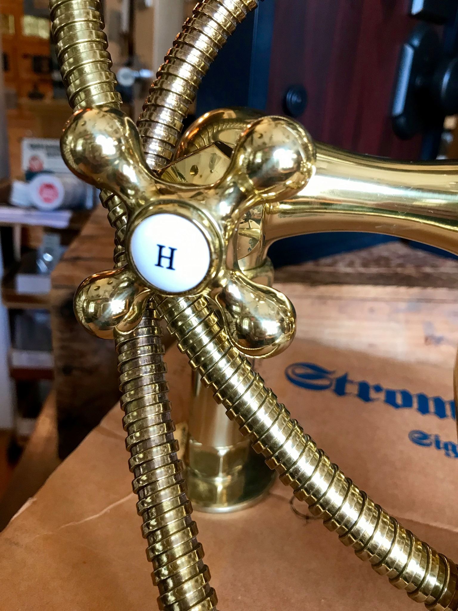Gold-colored faucet with a cross-shaped handle marked with an 