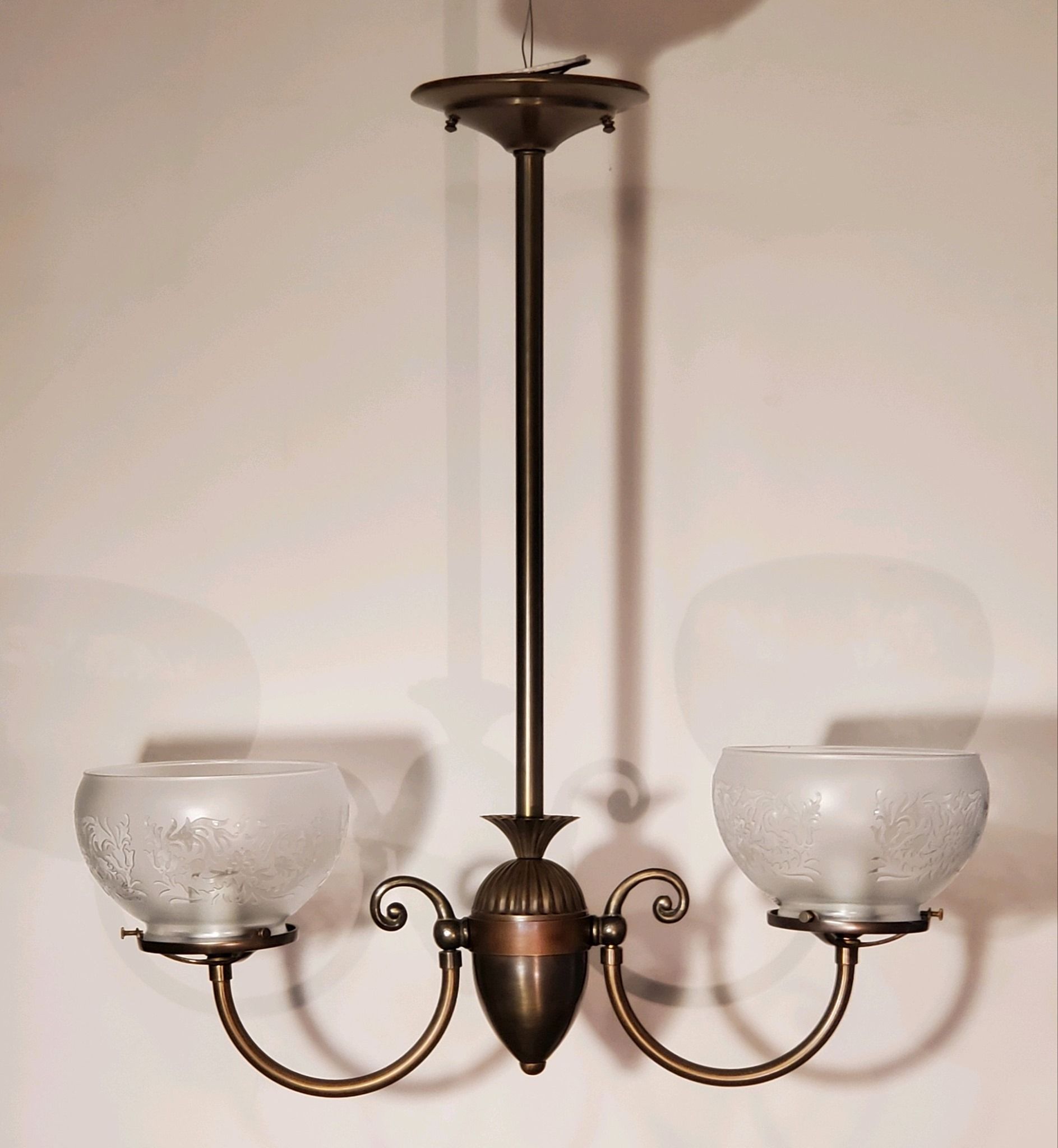 Bronze two-light chandelier with frosted glass shades, hanging from a ceiling.