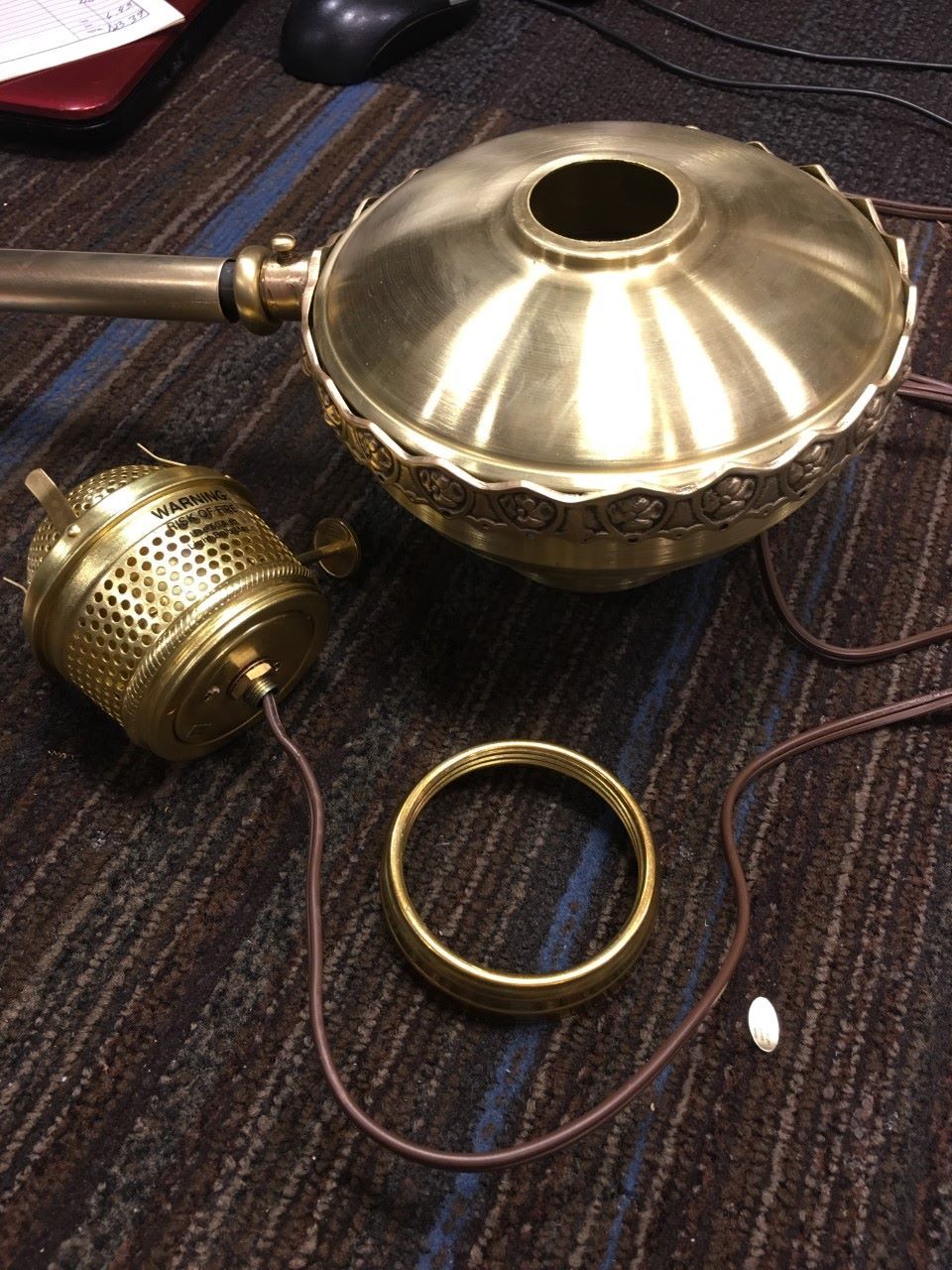Brass light fixture components disassembled on carpet.