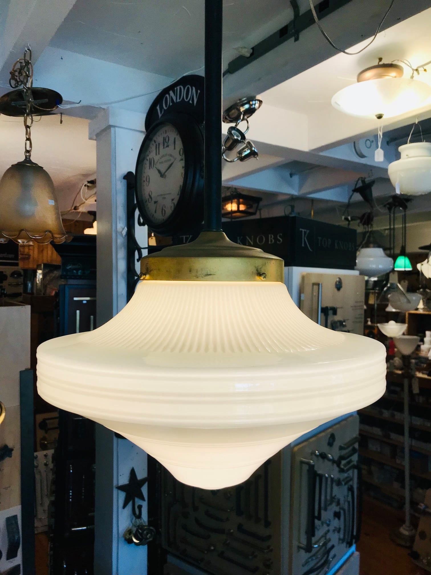White ribbed glass pendant lamp hanging in a shop, brass fixture, antique style.
