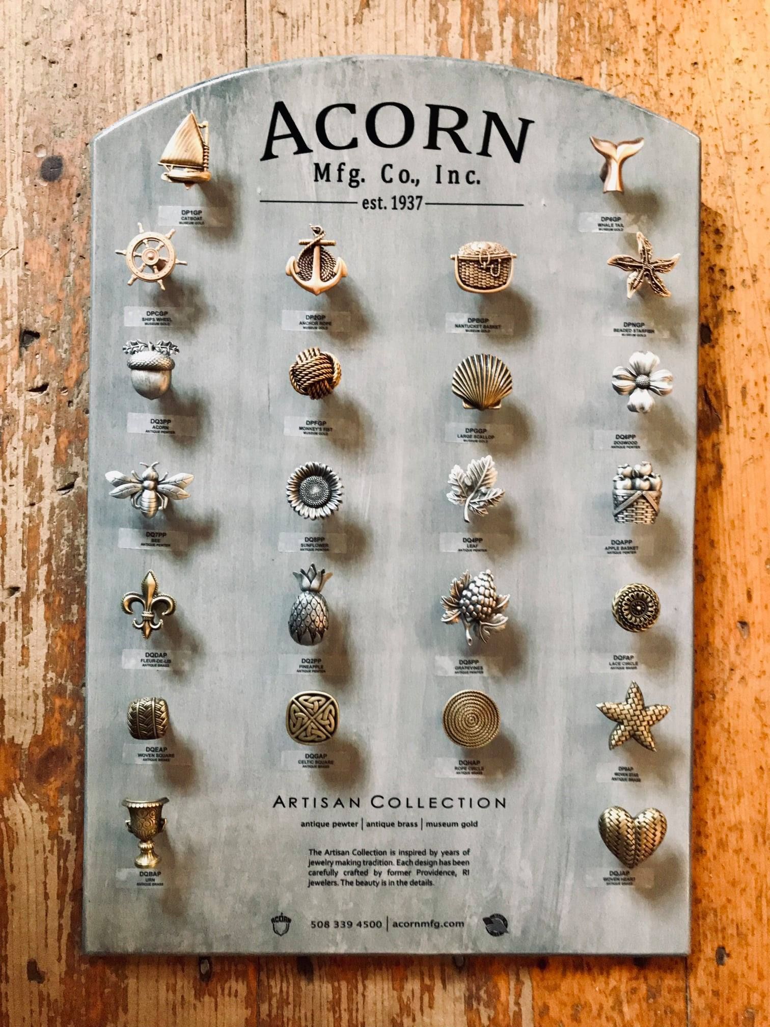 Display board showcasing various decorative knobs by Acorn Mfg. Co., mounted on a wooden wall.