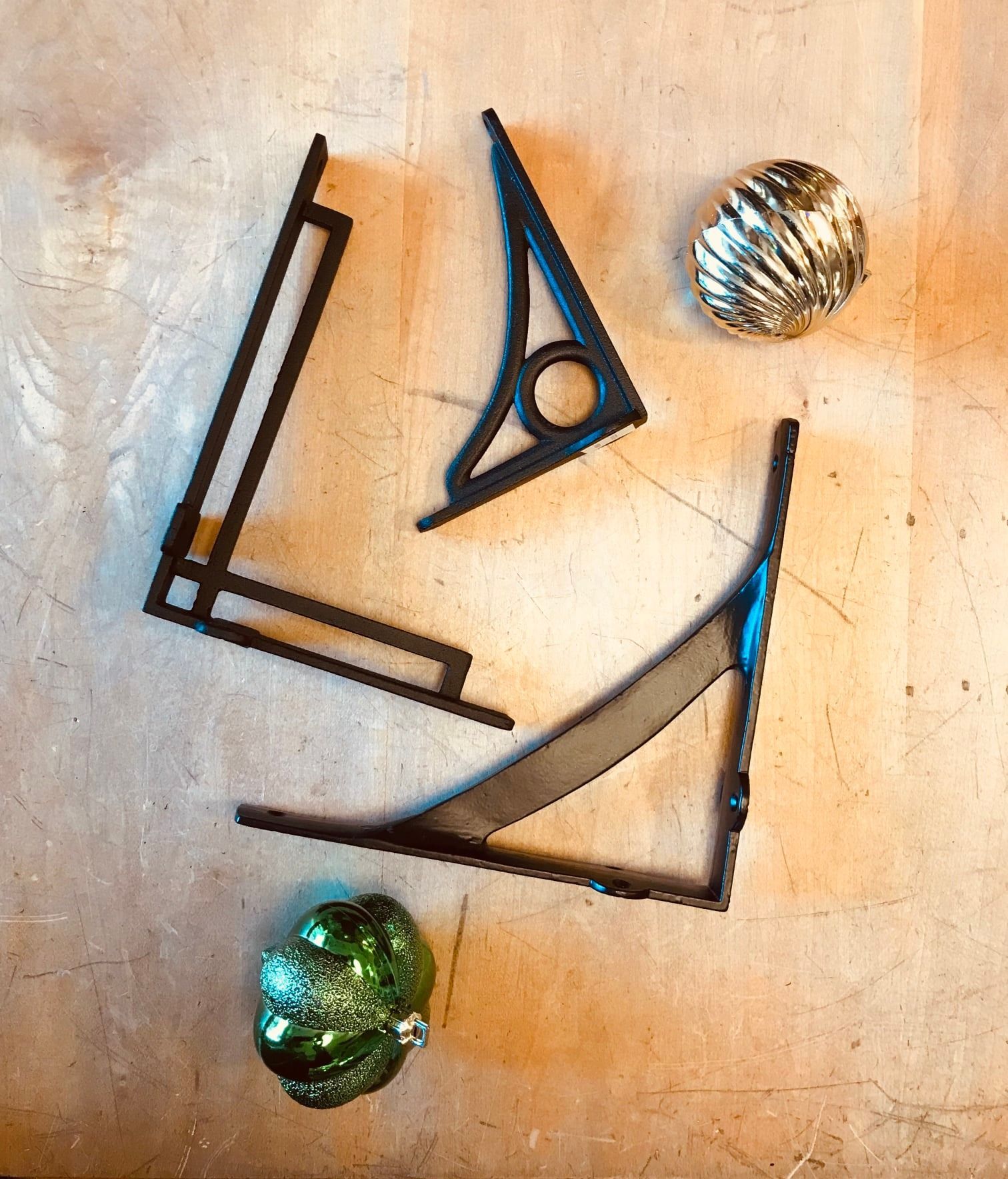 Black metal shelf brackets and decorative orbs on a light brown surface.