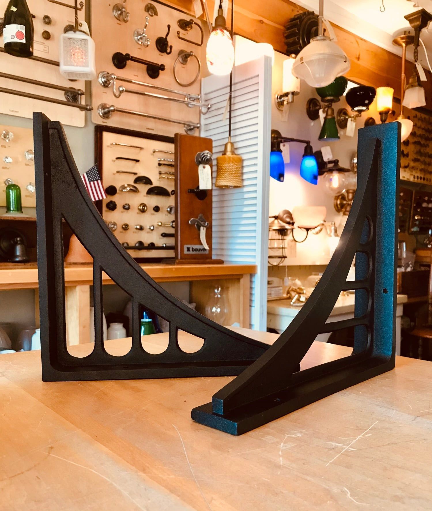 Two black, architectural-style shelf brackets on a wooden surface in a hardware store.