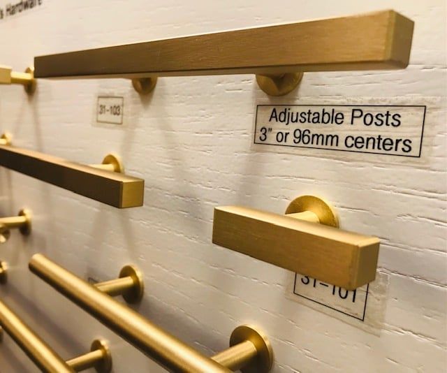 Close-up of cabinet hardware samples in gold. Rectangular handles on a display board.