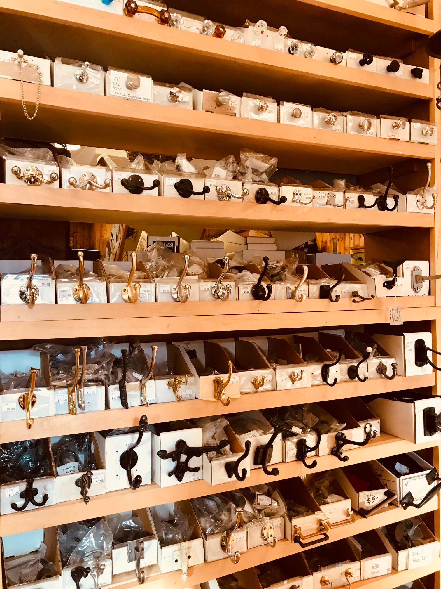 Shelves stocked with various knobs, hooks, and hardware displayed in boxes.