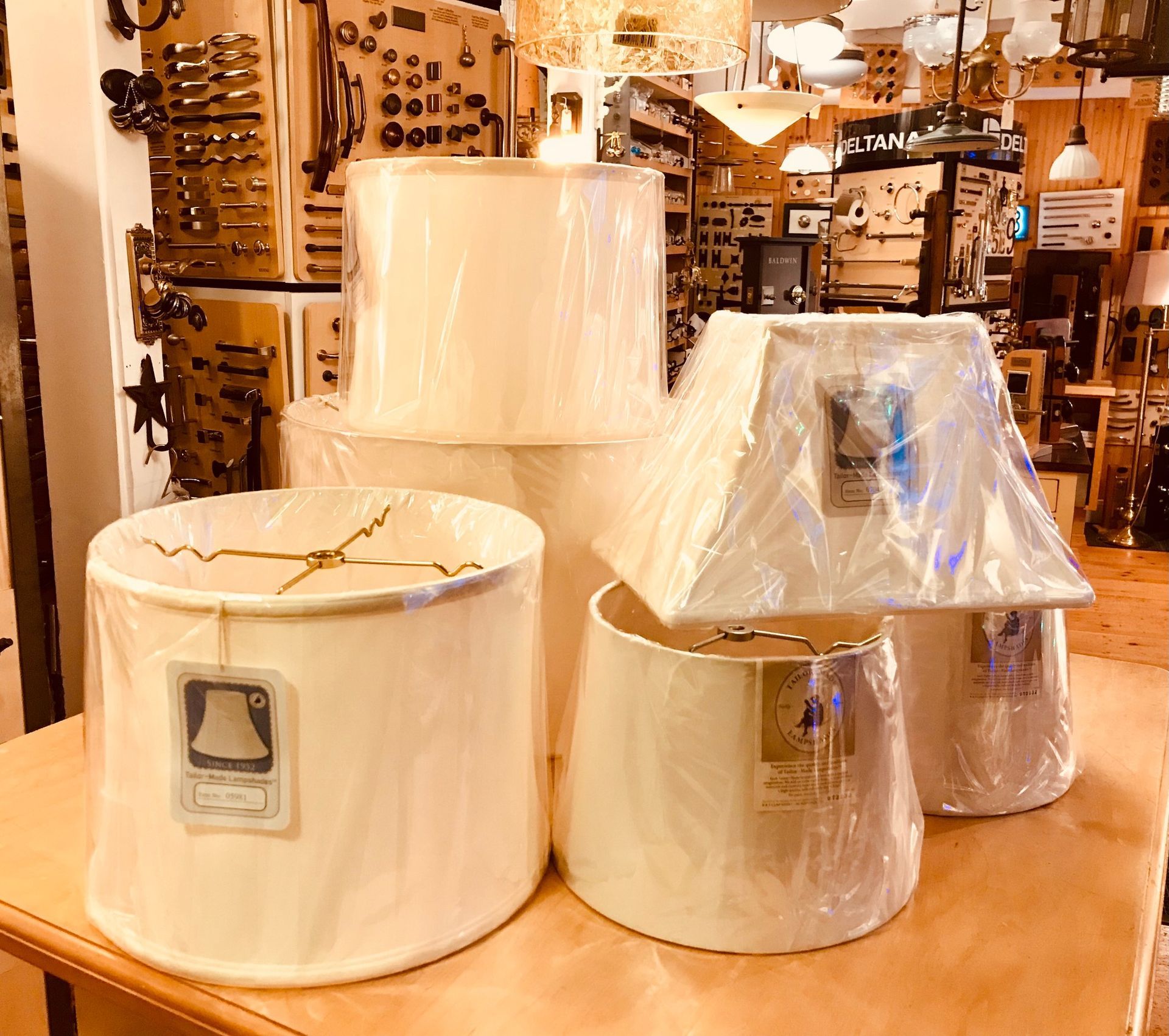Various beige lampshades, some in plastic, on a wooden table in a store.