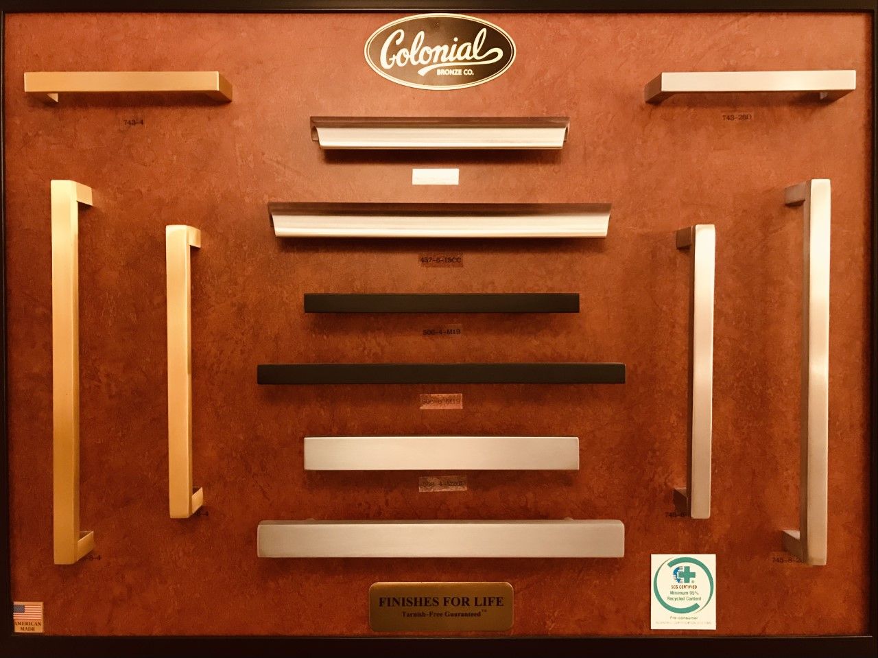 Display board showcasing various Colonial brand cabinet hardware pulls in different finishes.