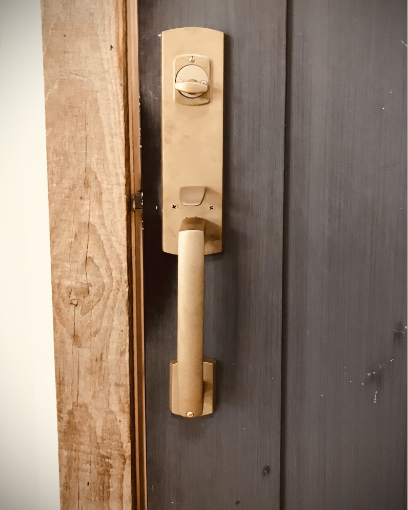 Wooden door handle on a gray door; natural wood frame on left.