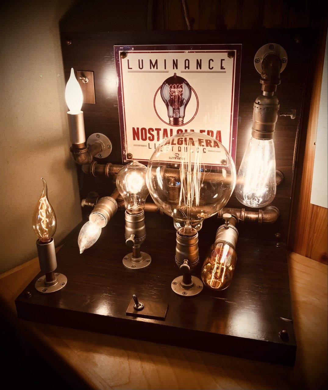 Steampunk lamp display with various glowing Edison bulbs, copper pipes, and a 