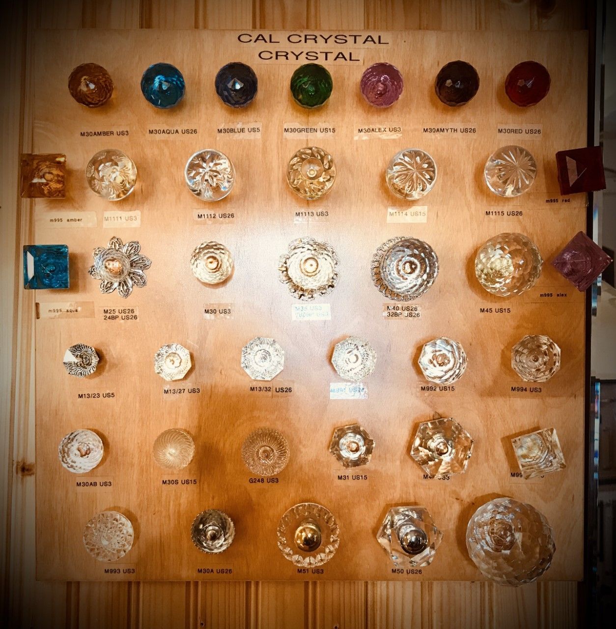 Wooden display board with various colored and shaped crystal knobs.