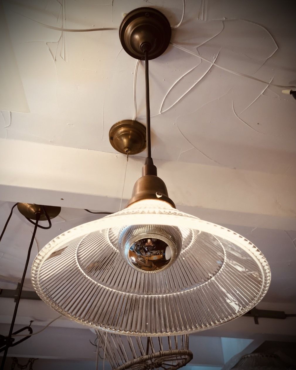 Antique pendant lamp with clear glass shade, brass hardware, and a round lightbulb.