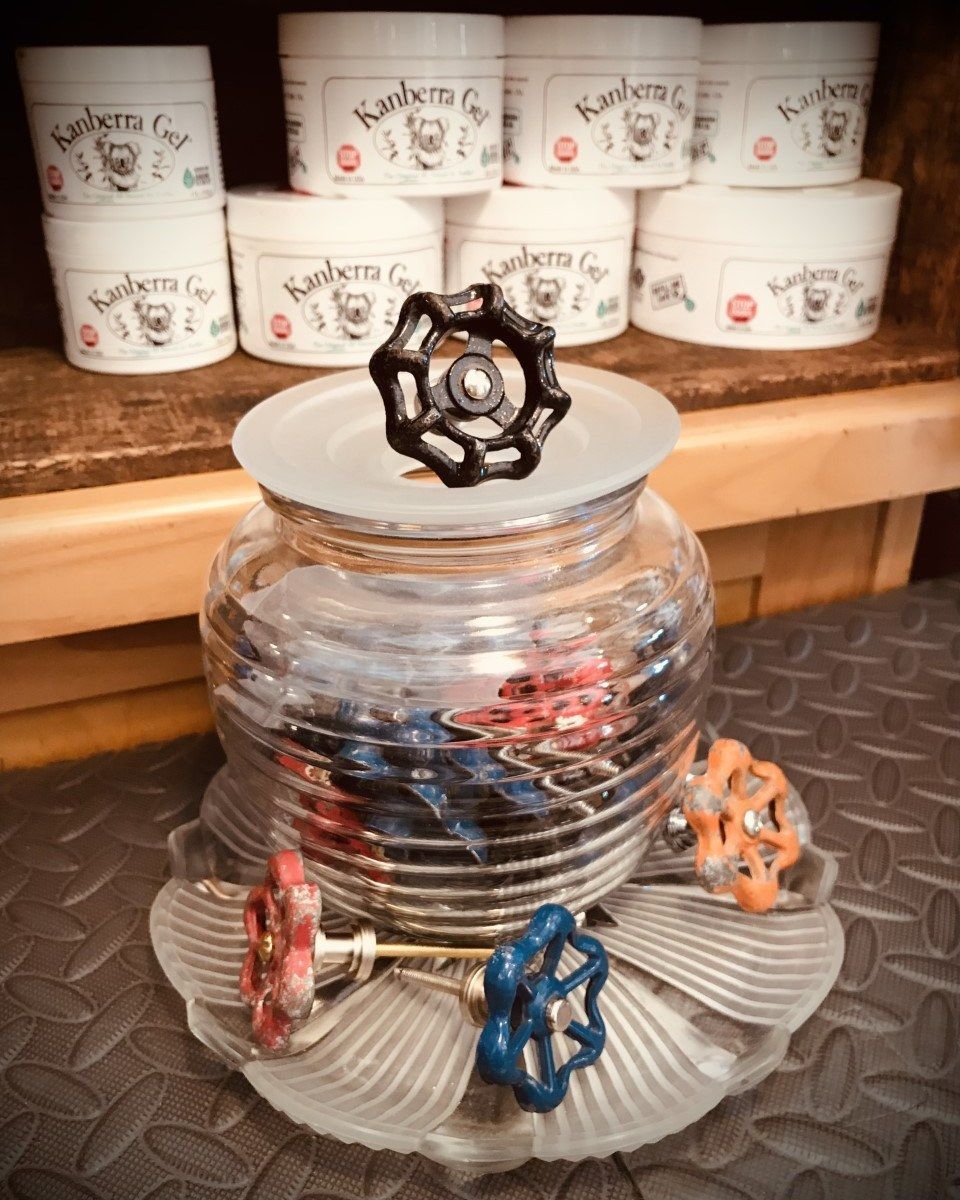 Glass jar with colorful handles, display of skincare products in background.