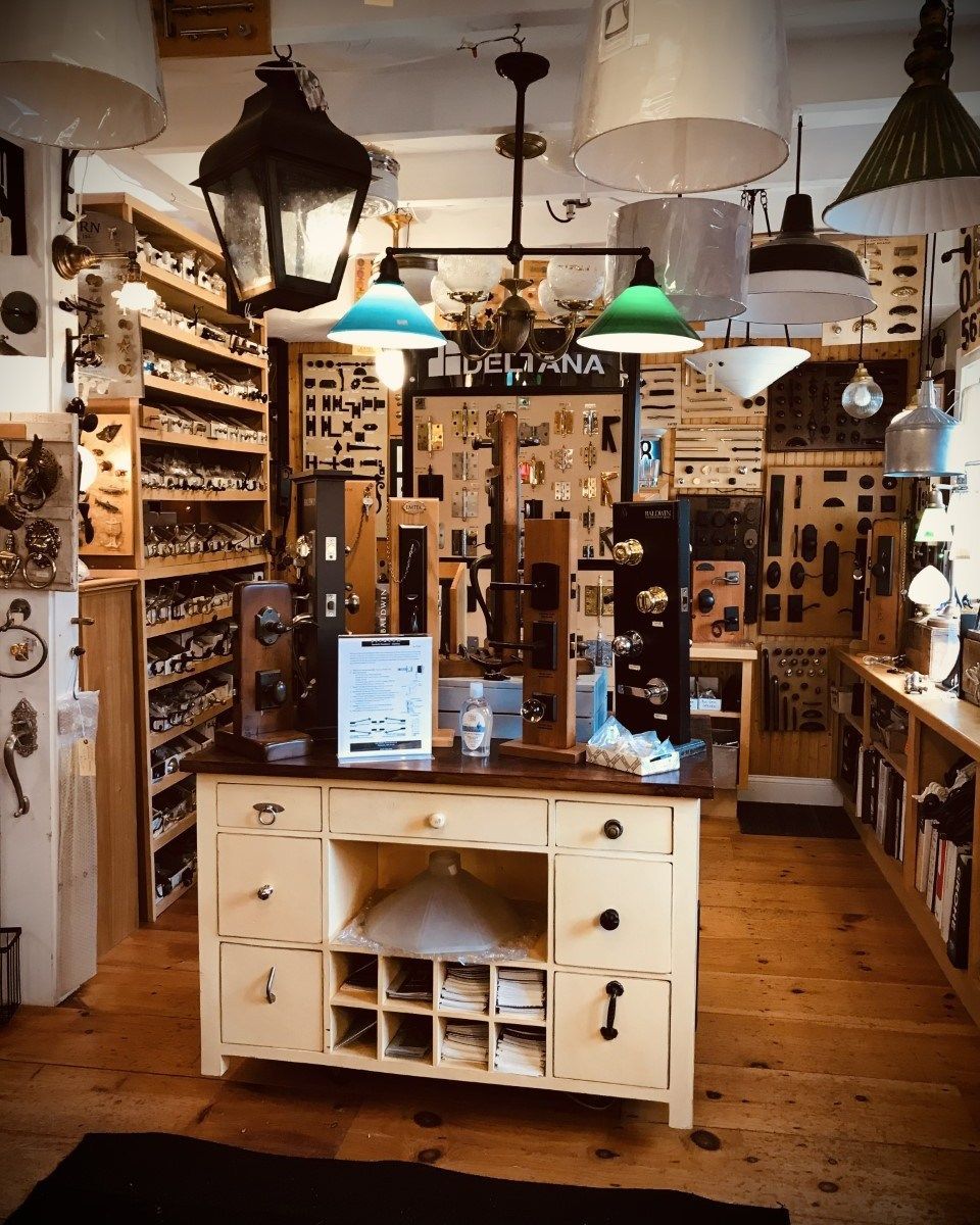 A hardware store interior. Displayed light fixtures and door hardware on shelving. Wooden floors and a central display.