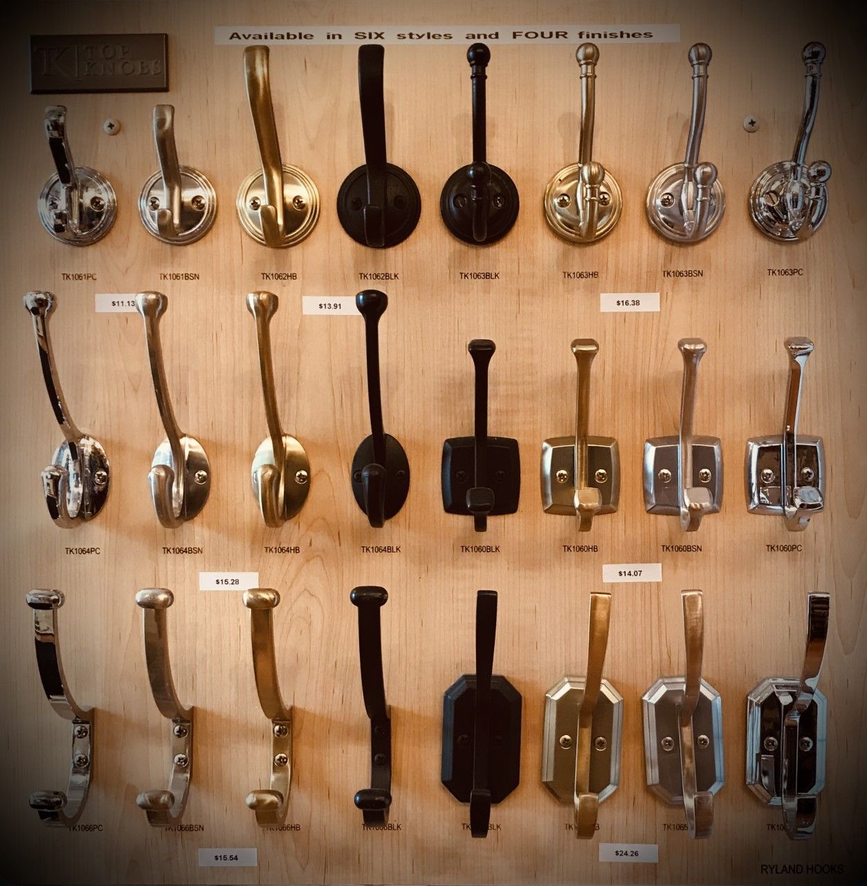Display of 21 vintage coat hooks in various styles and finishes, mounted on a wooden board.