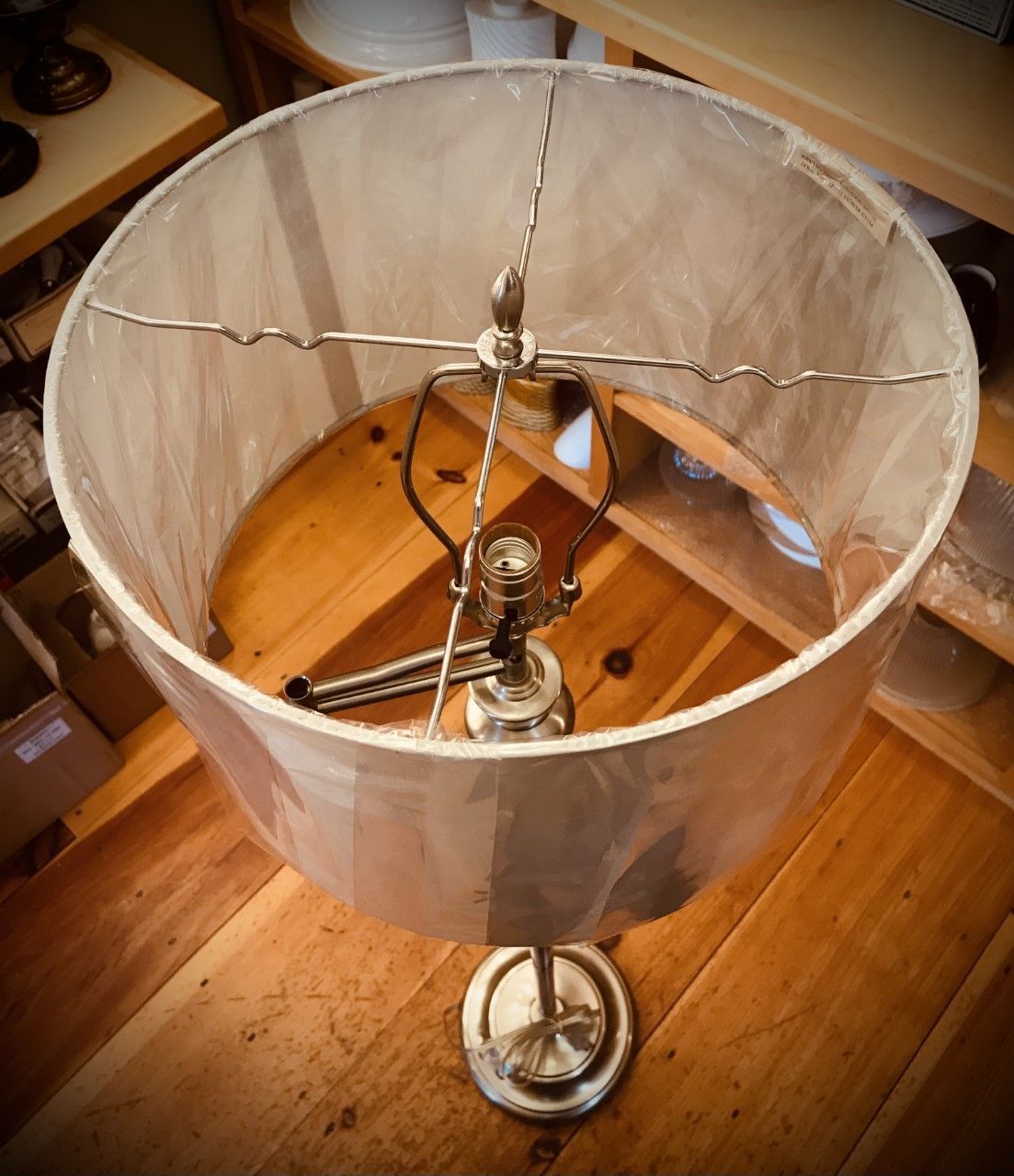 Lamp with a white lampshade and metal frame on a wooden surface.
