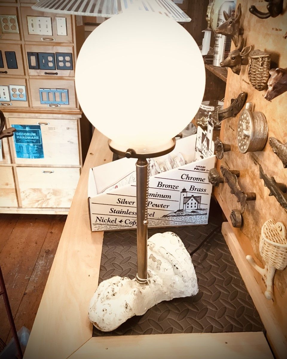 Lamp with globe shade on a bone-shaped base, sitting on a wooden counter.