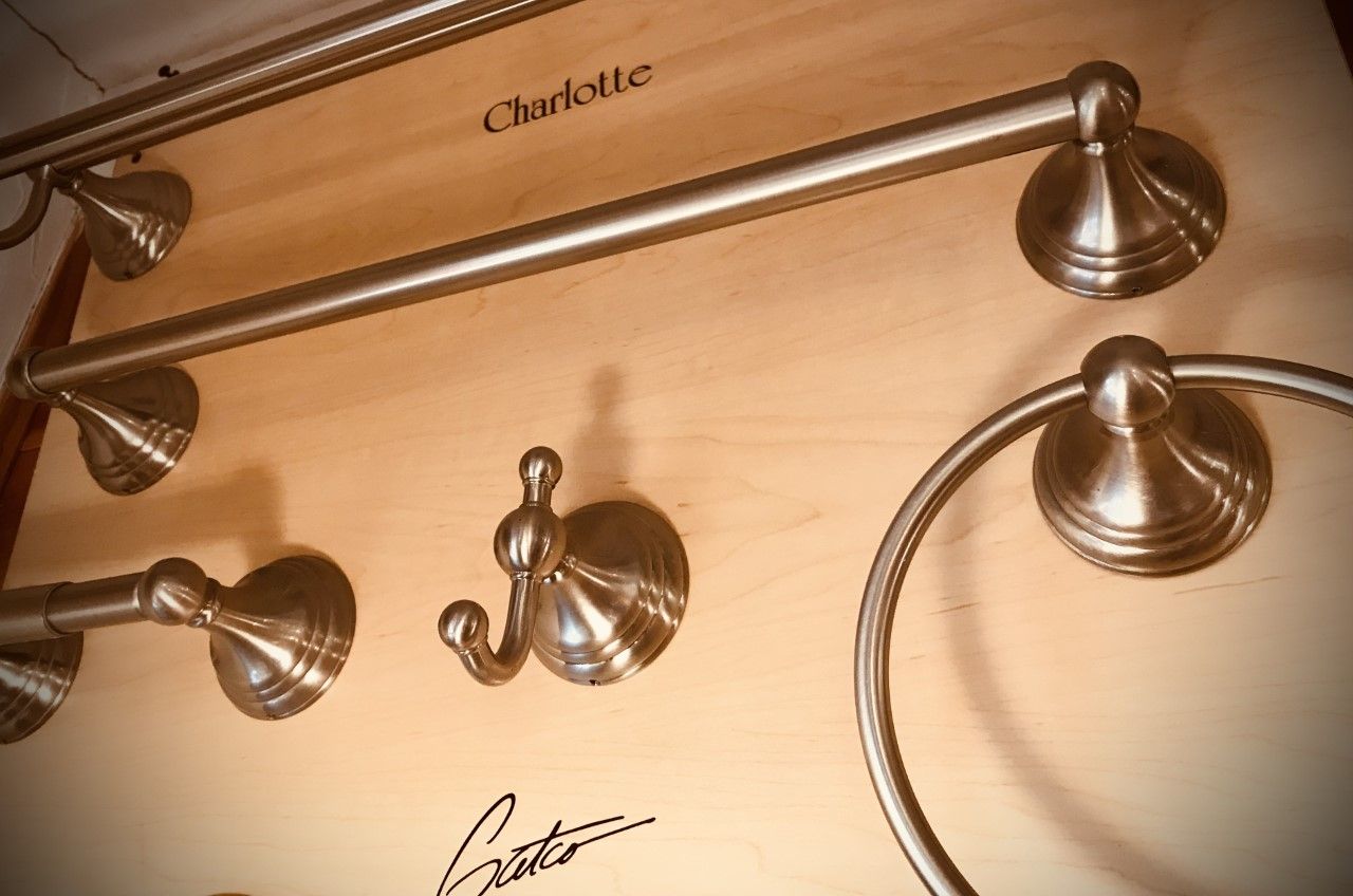 Bathroom fixtures in a brushed nickel finish mounted on a wooden board. 