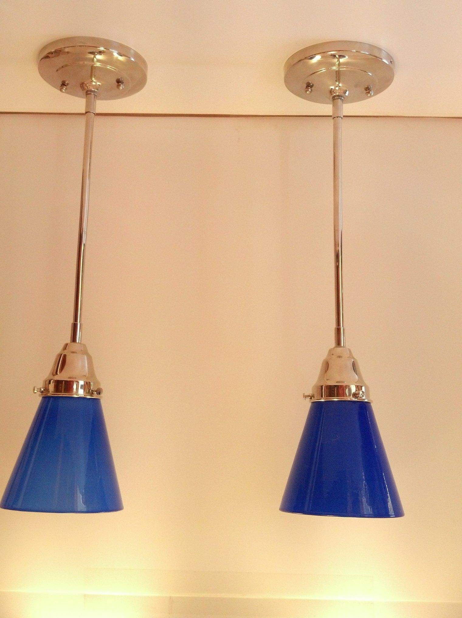 Two blue glass pendant lights suspended from a white ceiling.