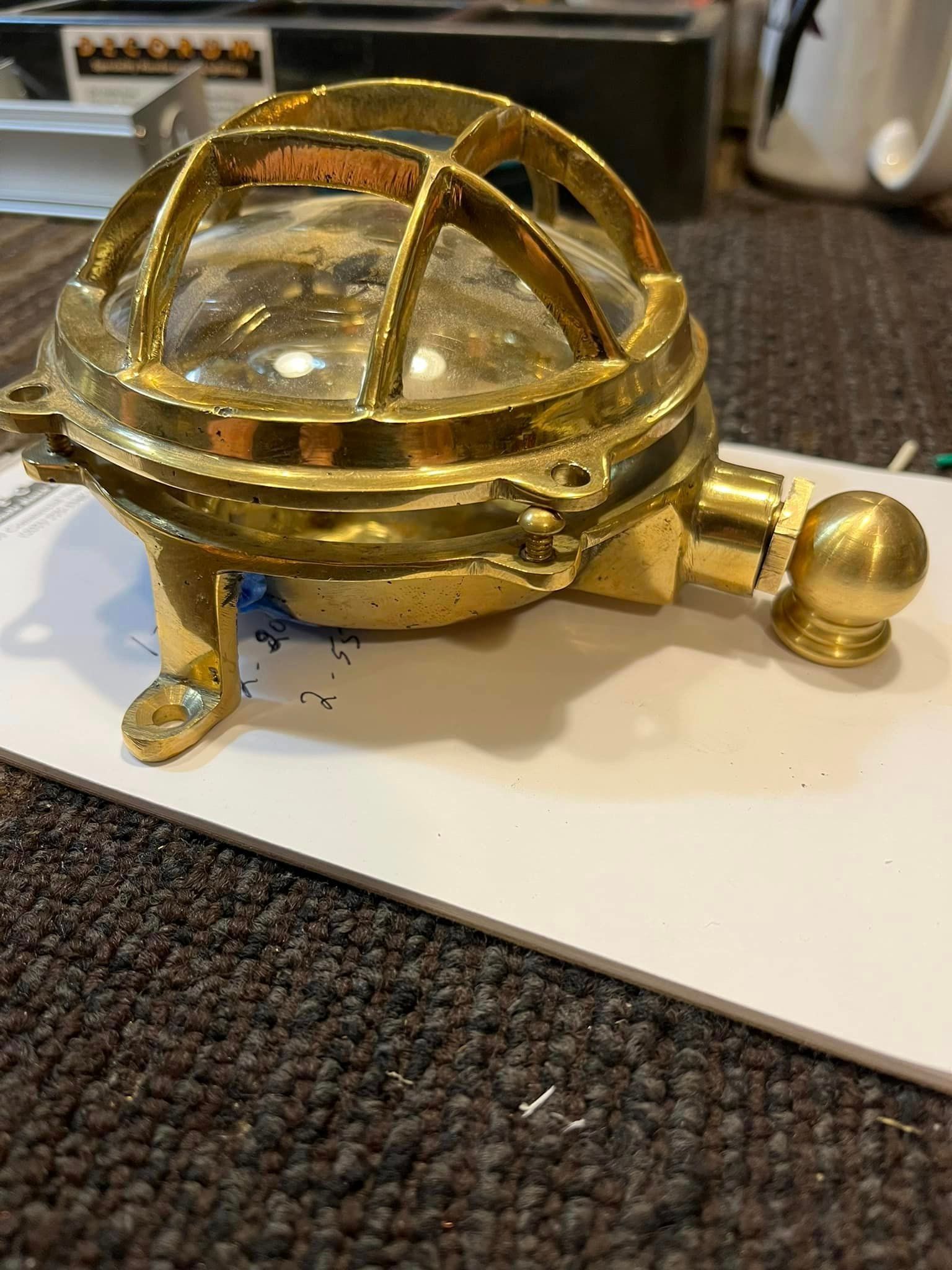 Brass nautical-style light fixture, with a caged glass dome and mounting brackets.